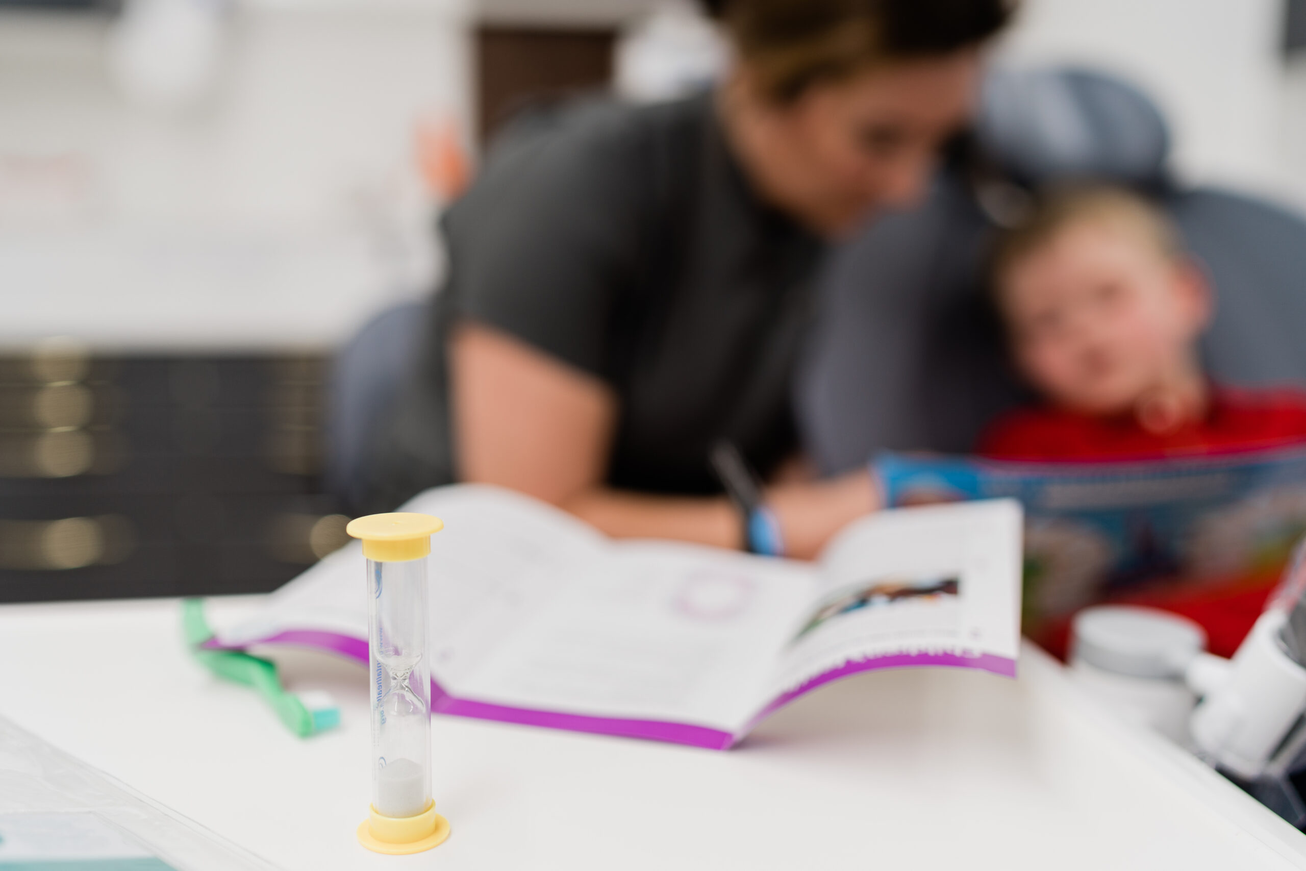 hour glass with a woman reading to a child in the background