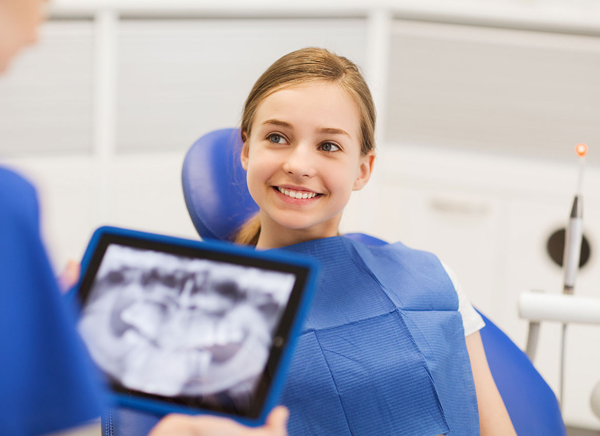 dentist looking at an x ray with a girl smiling